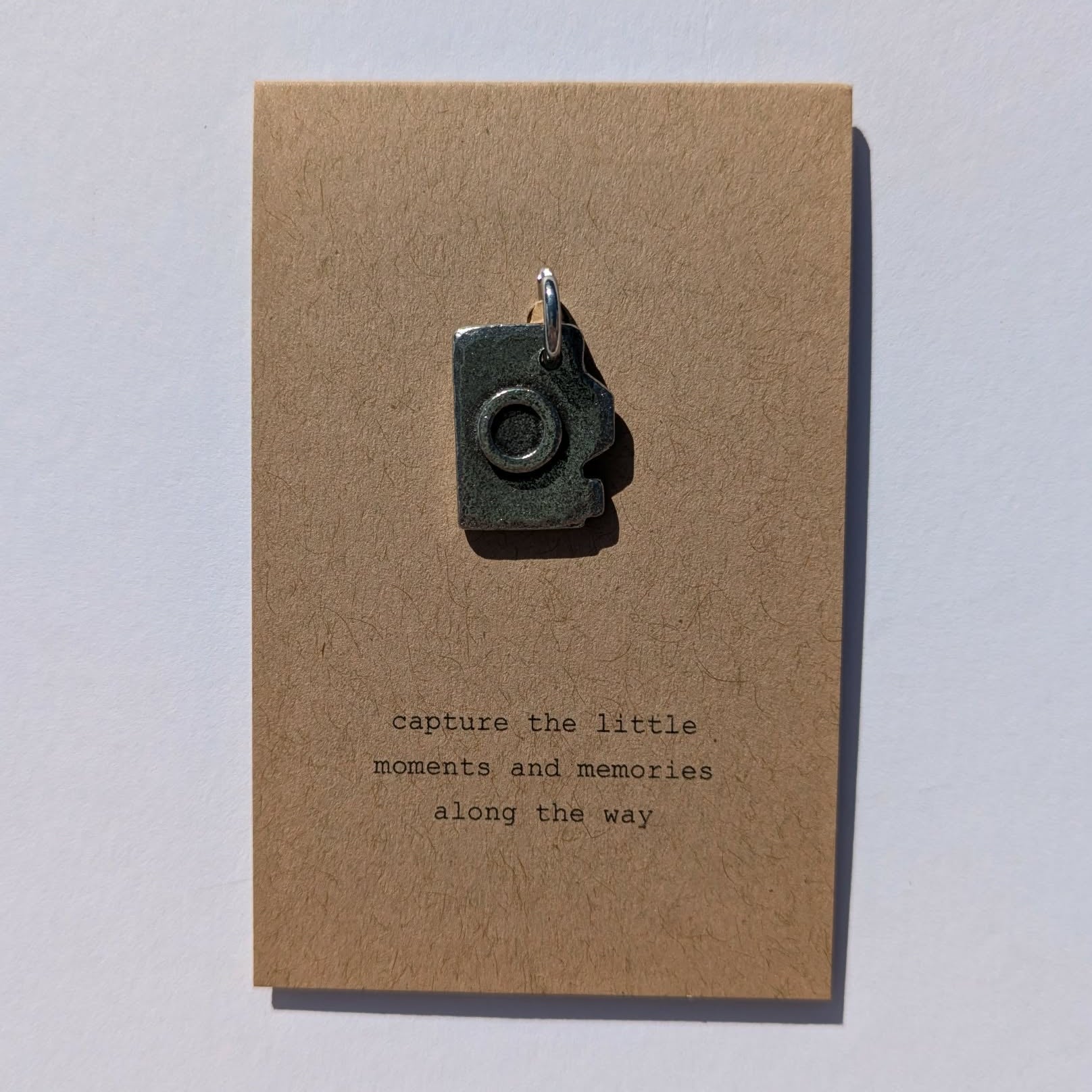 Brown card with a camera charm and text on a white background