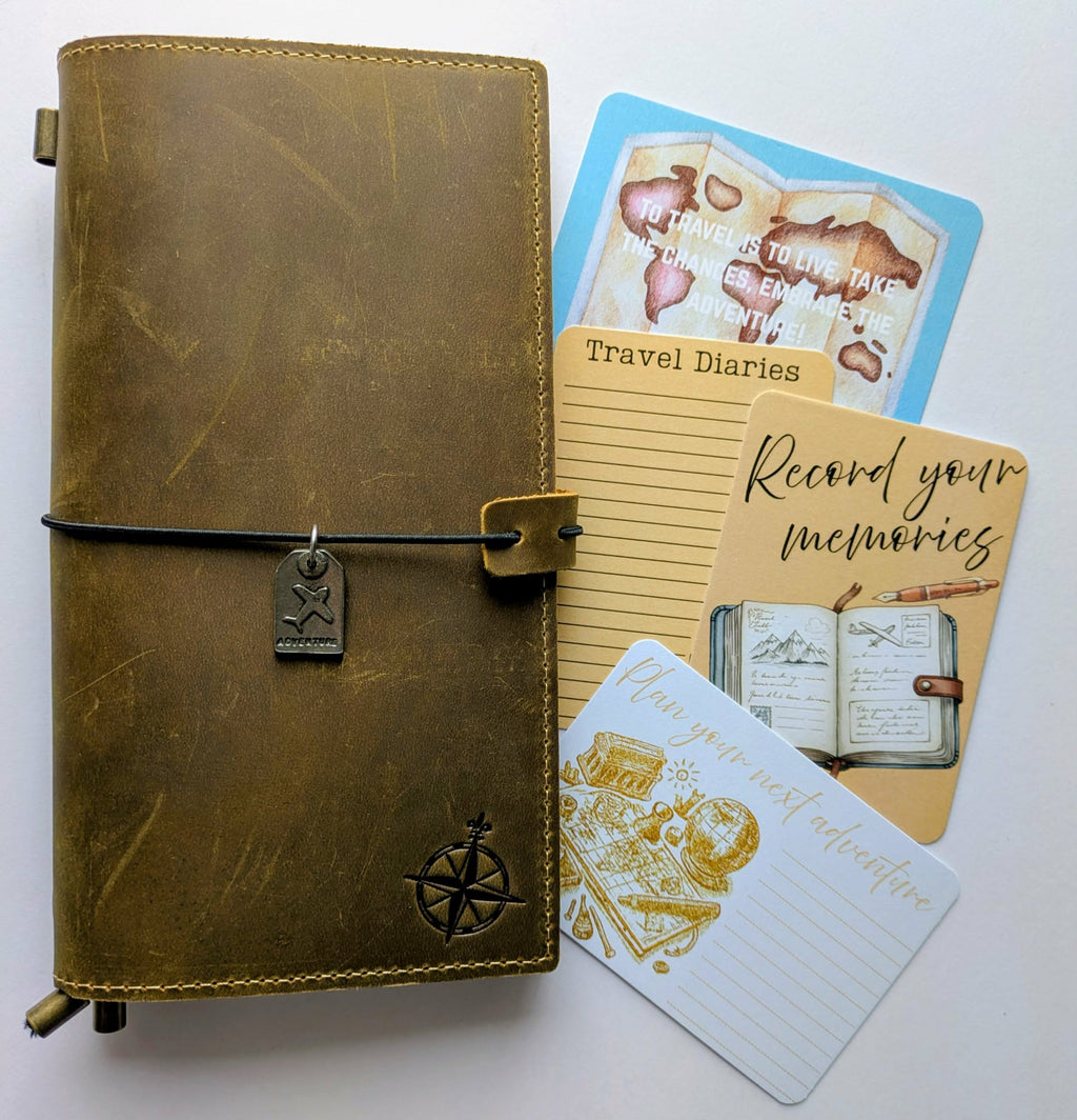 Brown leather travel diary with compass design, accompanied by travel-themed cards on a white background
