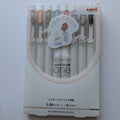A set of Uni-ball One gel pens in a white plastic case with a clear front window, showing 8 different colored pens inside. The packaging features a 'FIKA COLOR' sticker and the Uni logo in the top right corner.