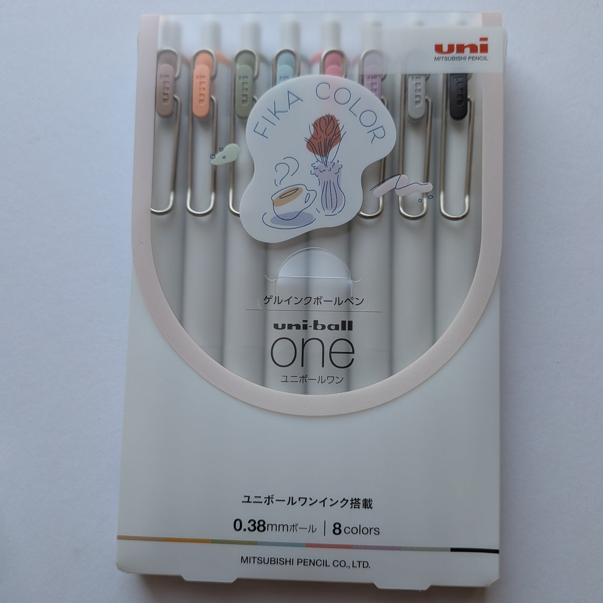 A set of Uni-ball One gel pens in a white plastic case with a clear front window, showing 8 different colored pens inside. The packaging features a 'FIKA COLOR' sticker and the Uni logo in the top right corner.