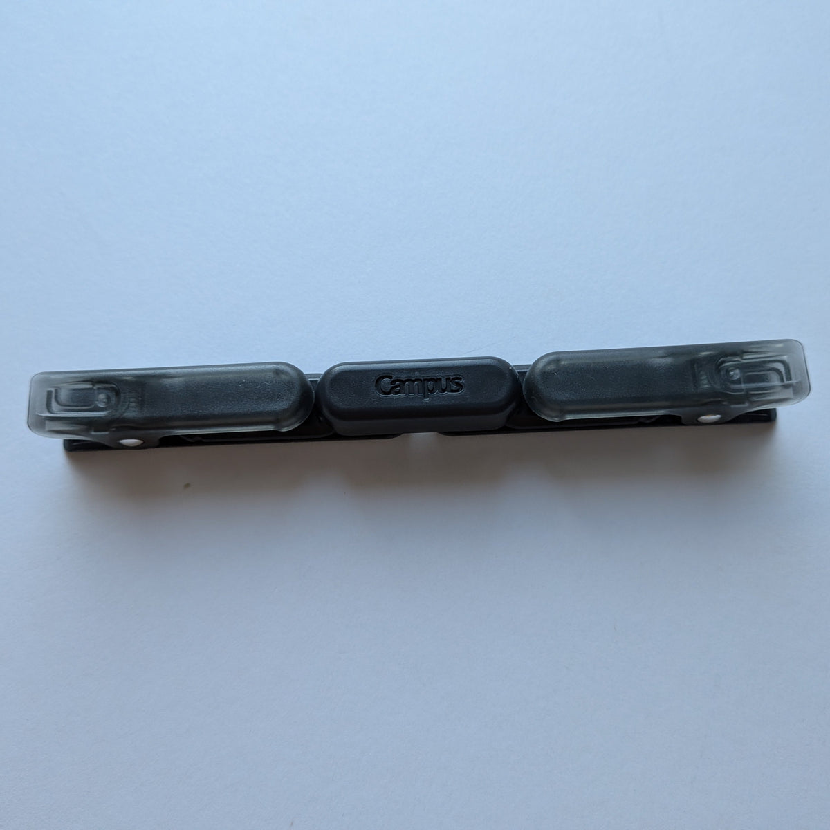 A Campus brand black plastic multi-hold binder clip with three transparent plastic prongs, shown folded on a plain white background.