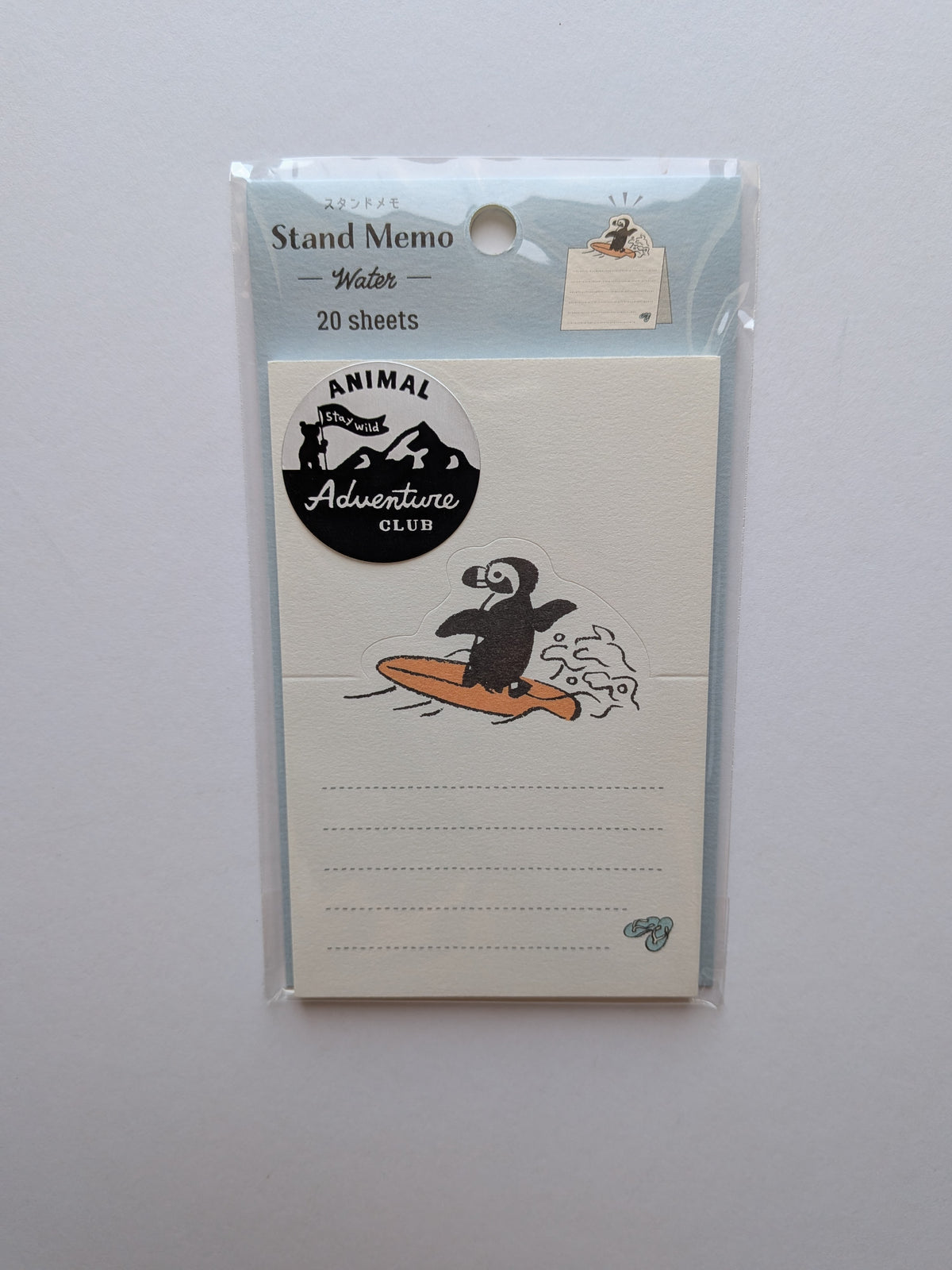 A packaged stand memo pad with a penguin on an orange surfboard illustration and the text 'Animal Adventure Club.' The top header reads 'Stand Memo Water 20 sheets.