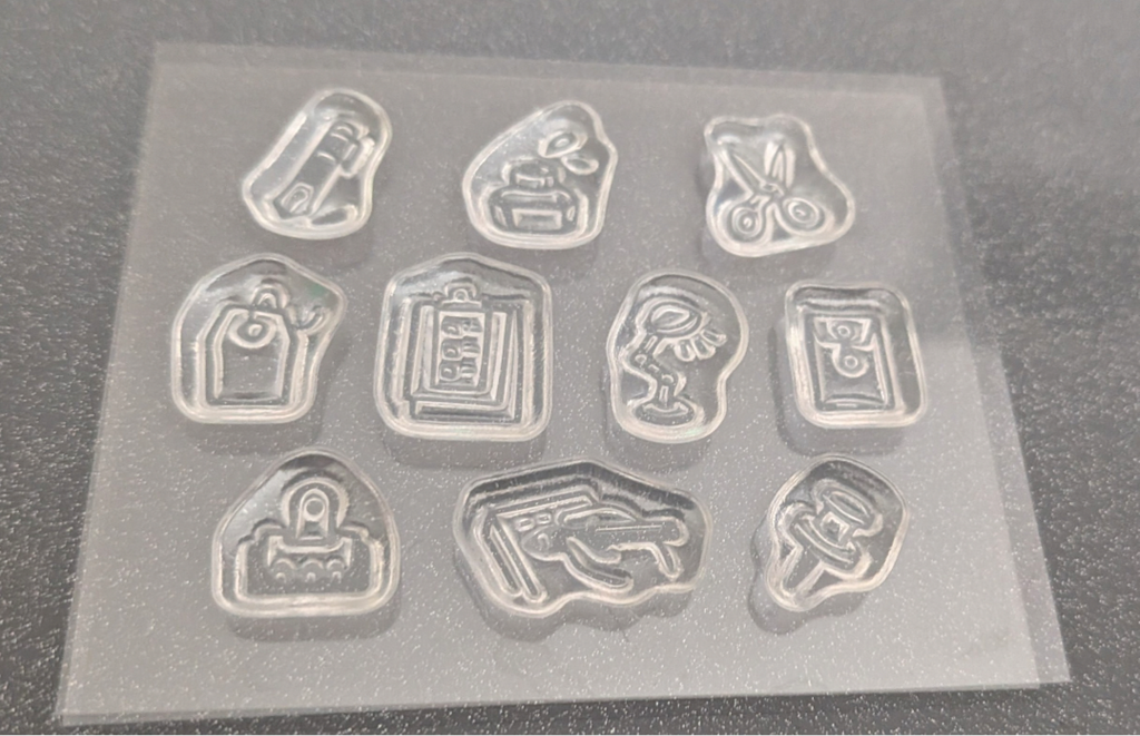 10 clear stamps individual embossed icons and symbols, photographed on a dark textured surface.
