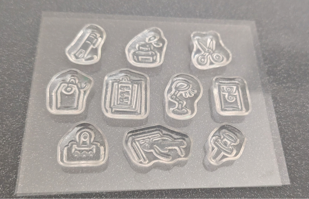 10 clear stamps individual embossed icons and symbols, photographed on a dark textured surface.
