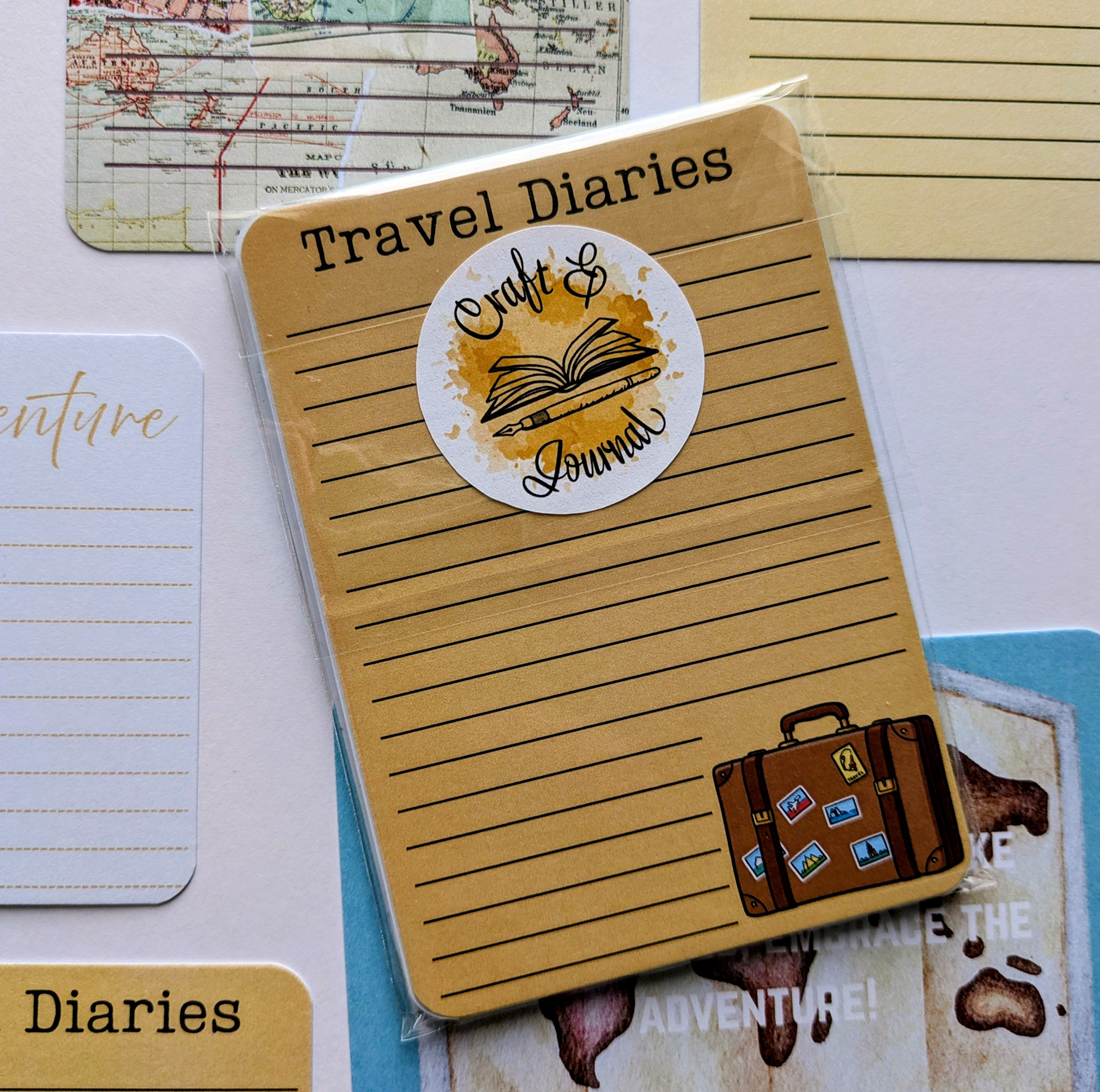 Notebook with 'Travel Diaries' and 'Craft & Journal' sticker on a decorative background with maps and travel-themed cards.