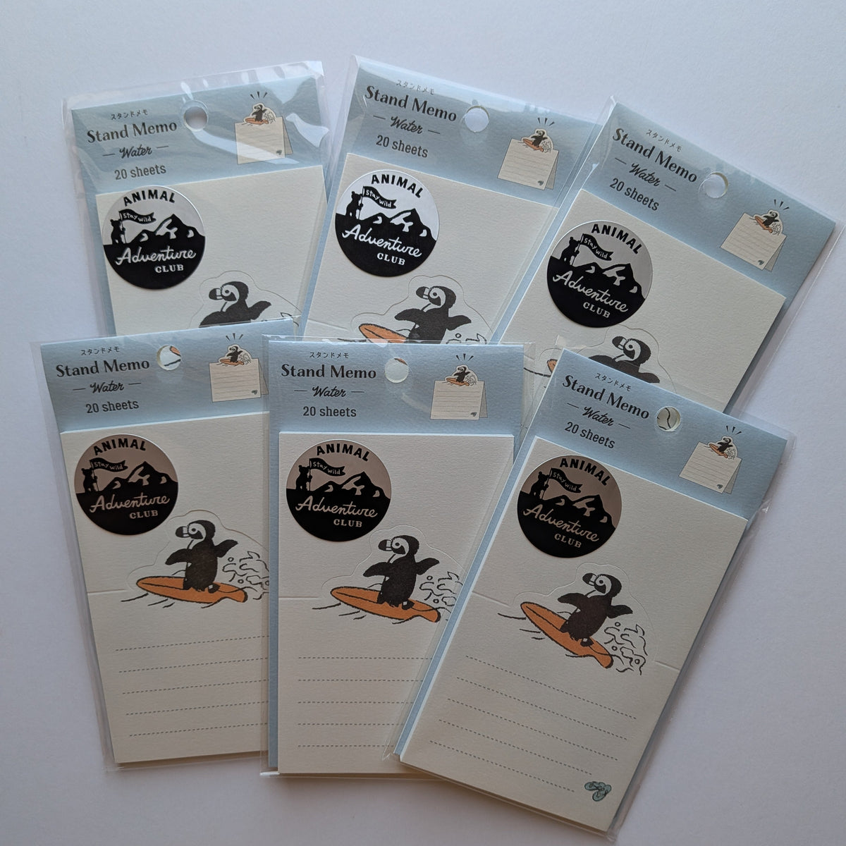 Five packages of Animal Adventures stand memo pads arranged on a plain white background. Each package contains 20 sheets of memo paper with a light blue header card and a cartoon penguin logo.