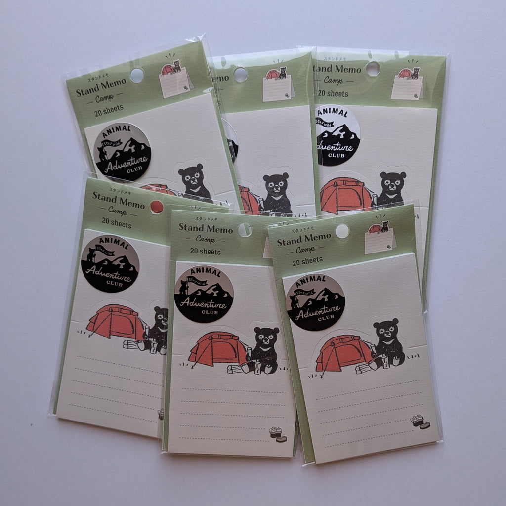 Six small packaged memo cards arranged on a plain light background. Each card package has a pale green border, a black-and-white mountain-and-bear logo.