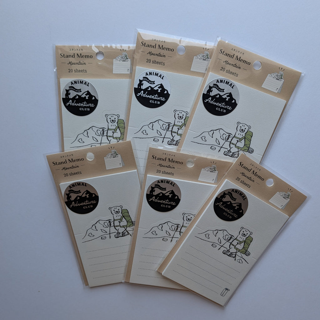 Six small lined notepad cards with kraft paper headers and a circular black-and-white logo, arranged on a plain light background.