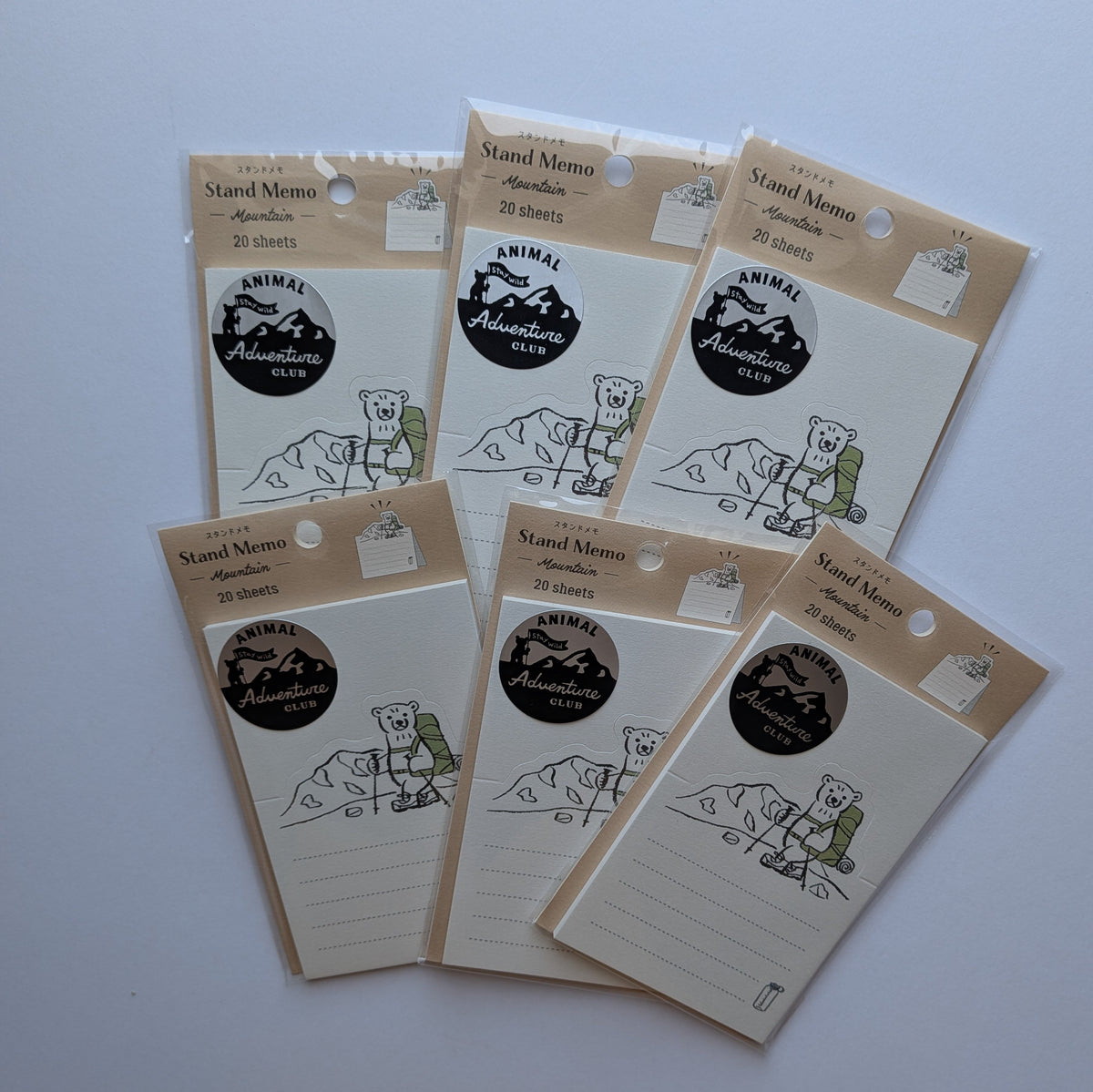 Six small lined notepad cards with kraft paper headers and a circular black-and-white logo, arranged on a plain light background.