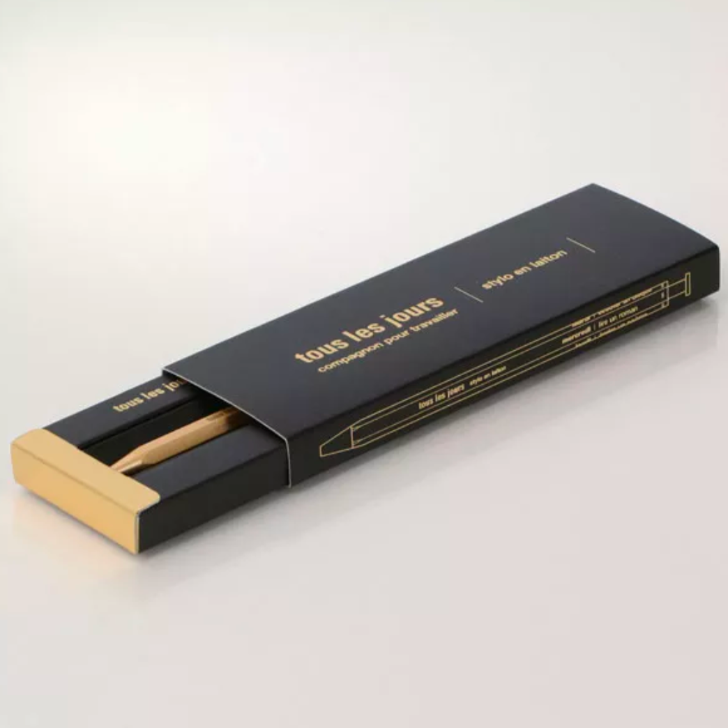 Black and gold pen packaging of 'tous les jours' on a white background
