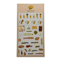 A sheet of cute desk-themed stickers on a beige backing card, displayed against a neutral light gray background. The stickers feature illustrations of fountain pens, notebooks, stamps, and text labels like 'Fountain Pen', 'Journal', and 'Document'.