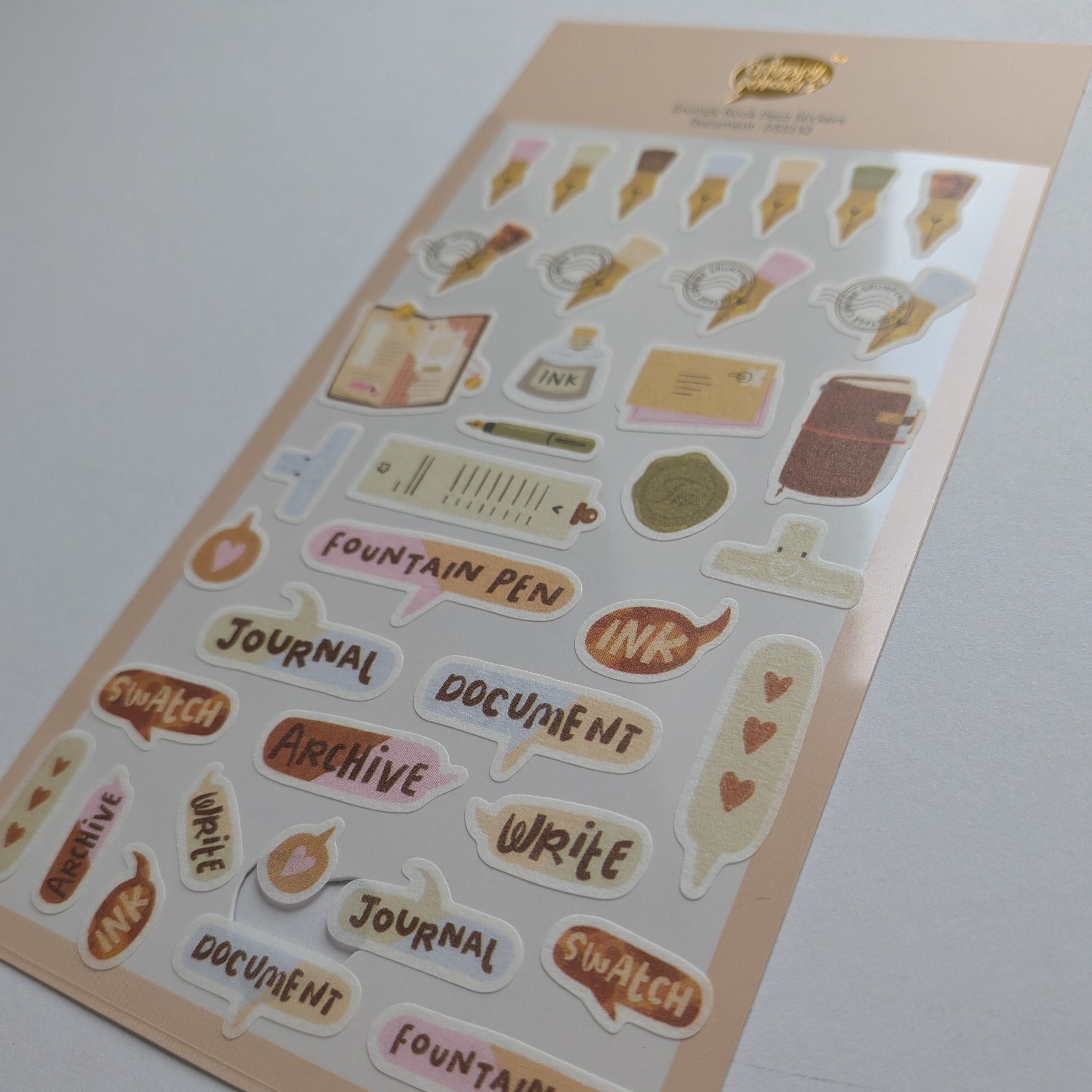 A sheet of cute, pastel-colored planner stickers featuring journaling and office-themed illustrations like fountain pens, books, and speech bubbles with words such as 'Fountain Pen', 'Journal', 'Document', and 'Archive'.
