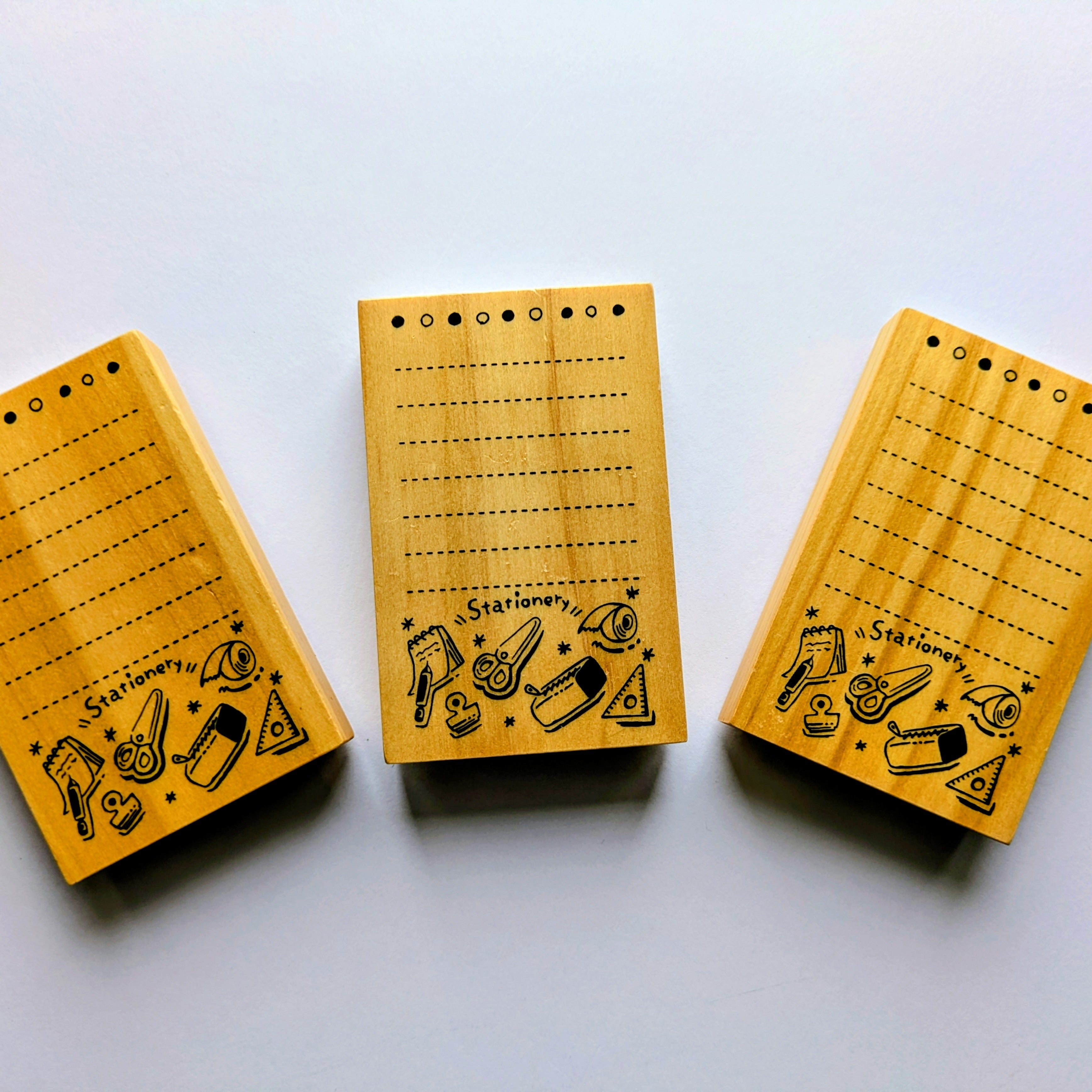 Three wooden stamps with black text and illustrations on a white background