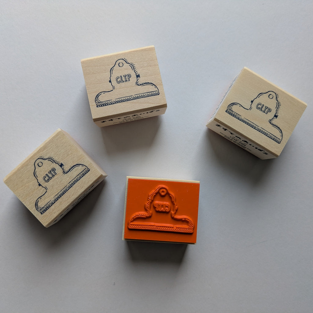 Four rubber stamps with a clip design on beige blocks.