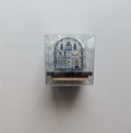 Small transparent box with a stamp design inside on a light gray background