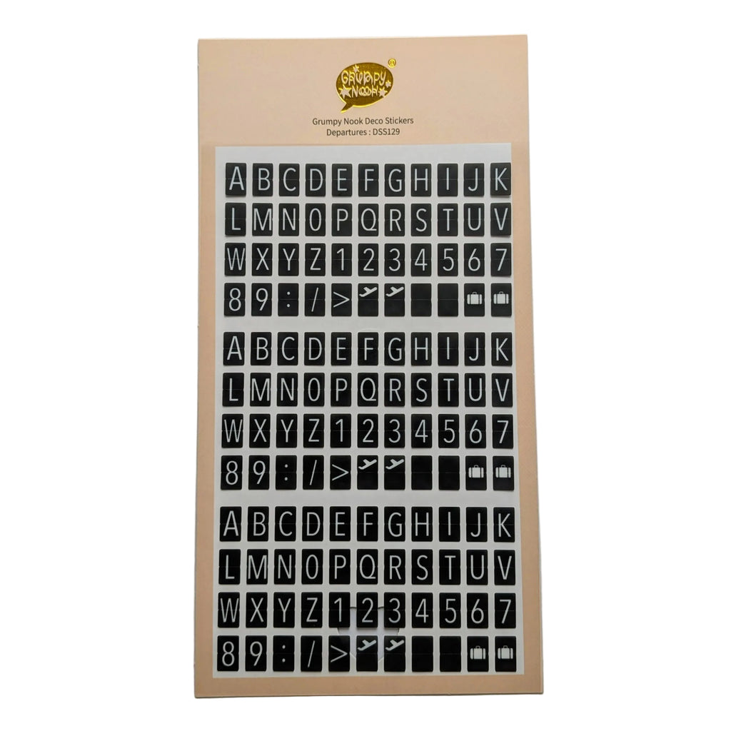 A sheet of alphabet and number stickers on a beige backing card, photographed against a plain light gray background. In the style of travel departures boards 