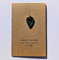 Metal map pin on a brown card with text 'memories are made with every pin on the map' on a light gray background
