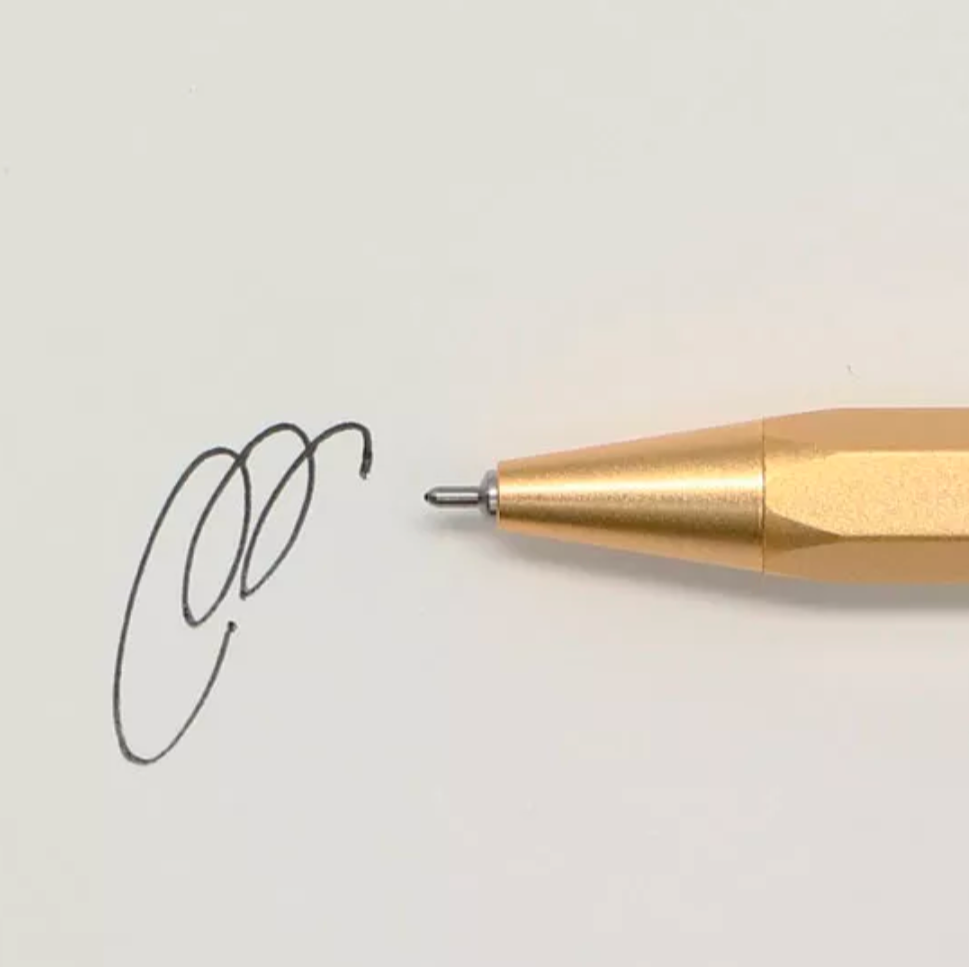 Gold pen tip drawing a small circle on a light gray background