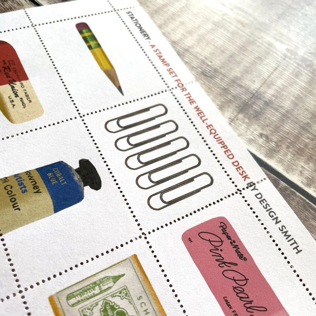Stationery item stamps including a pencil, bottle of ink, and paper clips on a white surface with 'Design Smith' branding.