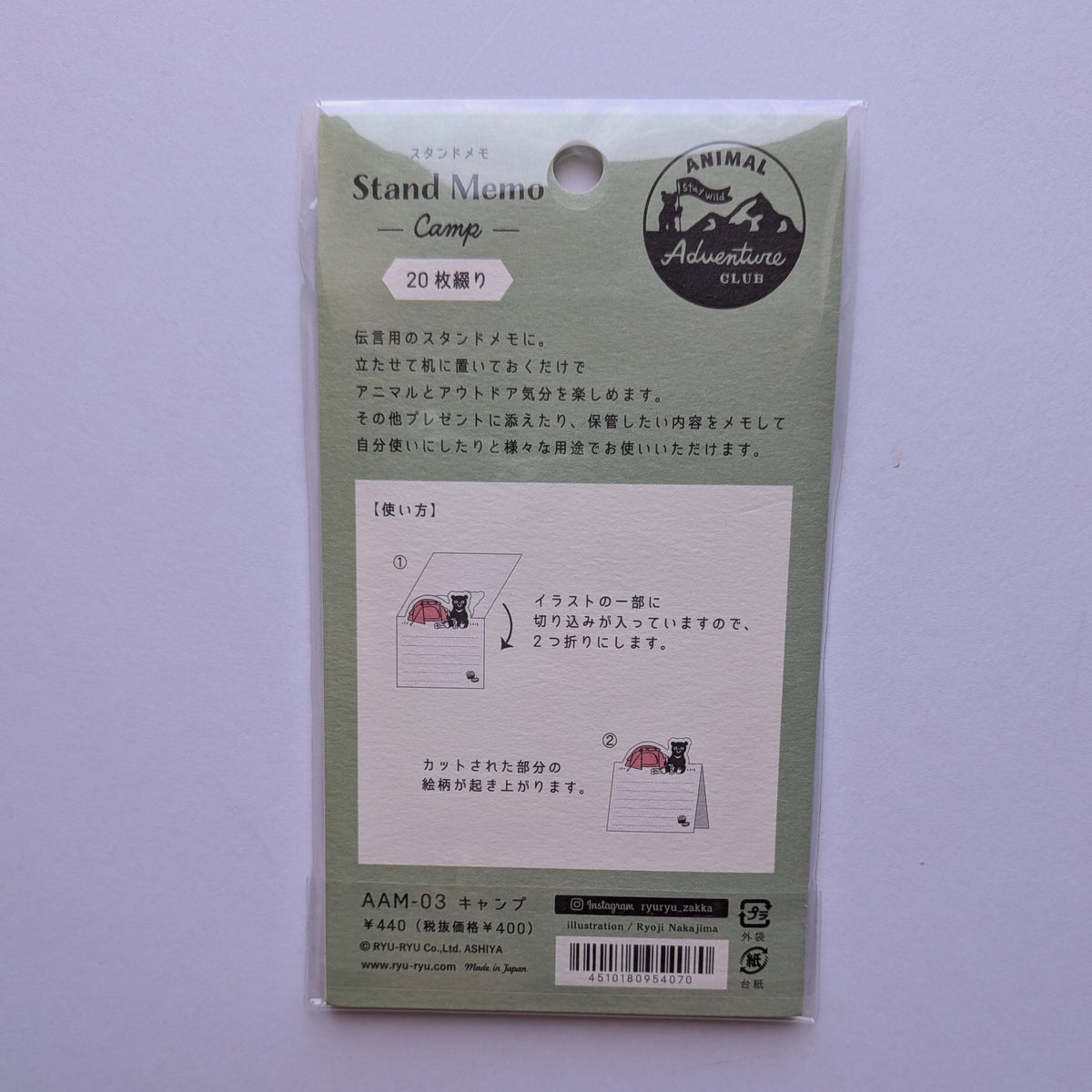 A packaged Japanese 'Stand Memo Camp' memo pad set by Animal Adventure, shown in its original light green carded packaging against a light lavender background.