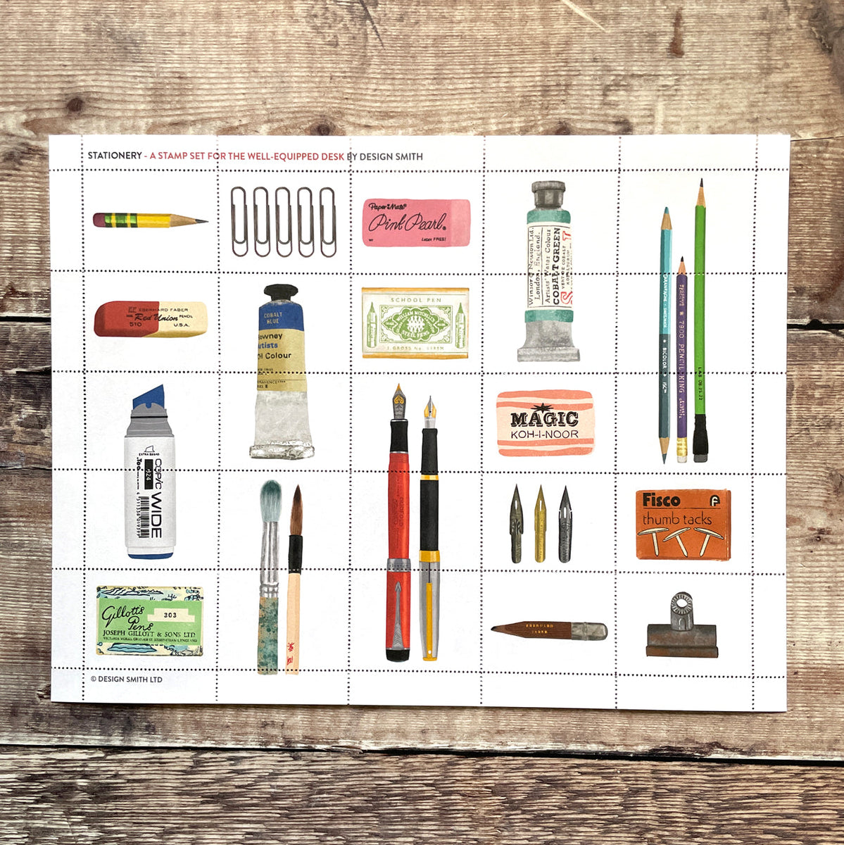 Sheet of stamps with stationery items on a wooden surface
