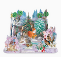 A colorful 3D pop-up cardboard forest scene featuring woodland animals such as foxes, rabbits, deer, a owl, and birds among decorated Christmas trees, flowers, and snowy ground on a white background.