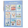 A sheet of nine Los Angeles postage stamps displayed in a clear protective sleeve, placed on a dark wooden surface. The sheet is labeled 'LOS ANGELES' at the top and features various colorful illustrated stamps representing different neighborhoods and landmarks.