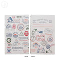A notebook showing both front and back covers decorated with colorful travel stamps, postmarks, and illustrated stamps in red, blue, and black ink on a white background.
