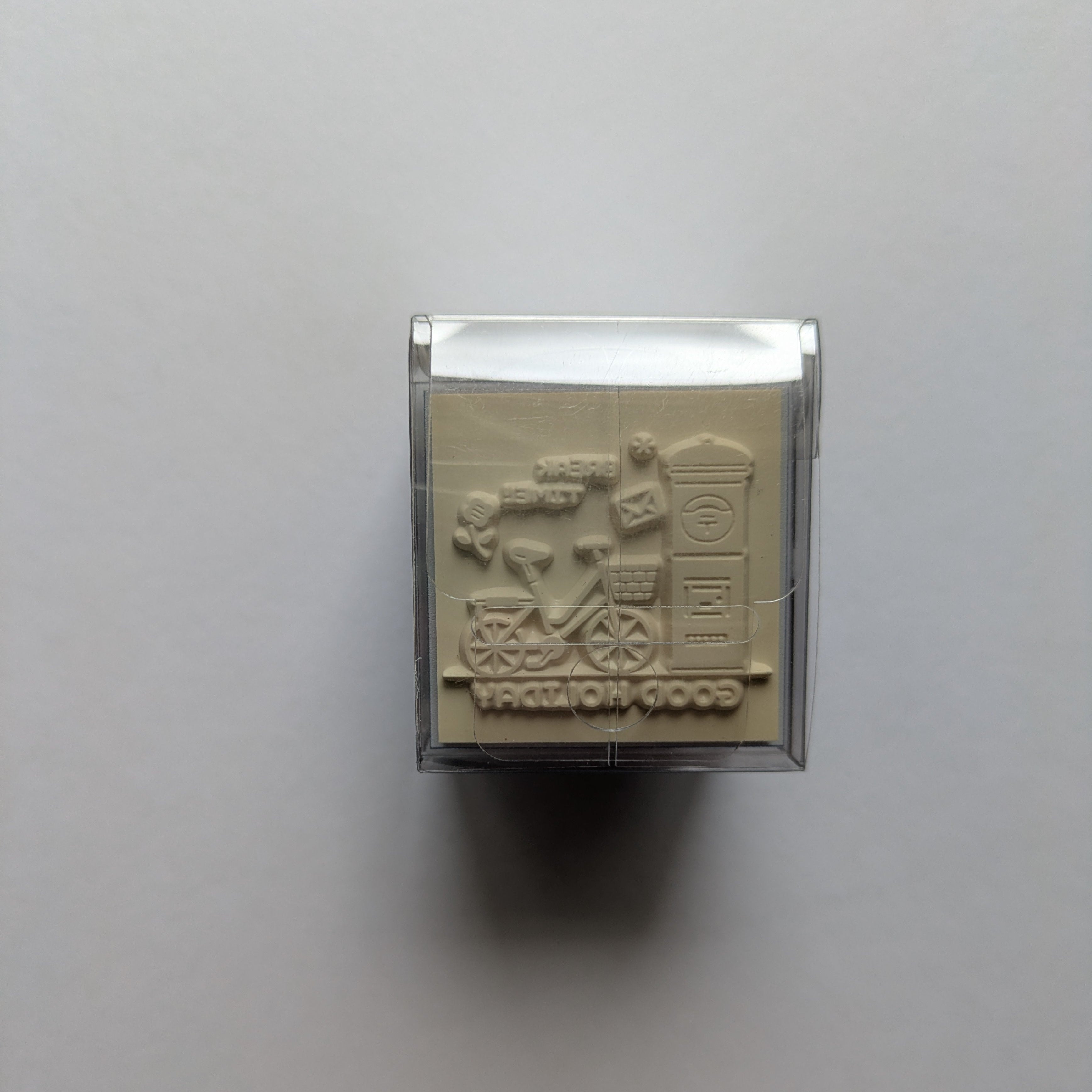Rectangular rubber stamp with a design on a light gray background