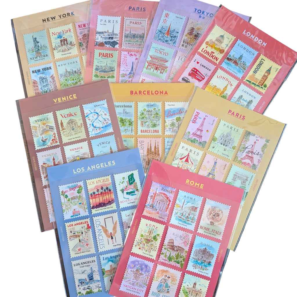A set of colorful travel-themed stamp sheets arranged on a dark wooden surface. The sheets feature different city stamps including New York, Paris, Tokyo, London, Venice, Barcelona, Los Angeles, and Rome, each in its own pastel-colored protective sleeve.